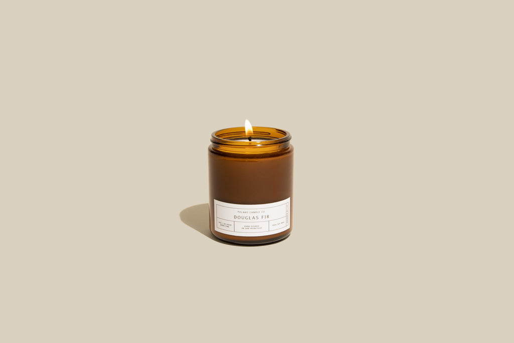 Douglas Fir candle in an amber jar, glowing softly, capturing the essence of a fresh forest breeze for a cozy ambiance.